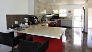 Cocina moderna con una isla central, electrodomésticos de acero inoxidable y una pared de acento roja.
