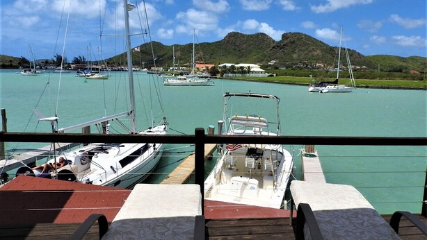 Un puerto deportivo con barcos amarrados, vista al agua y una cadena montañosa distante.