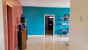 Um corredor amplo com piso de madeira, parede azul decorativa e um sapateiro.