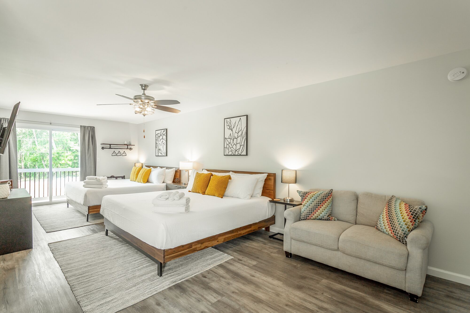 A modern hotel room with a large bed, a sofa, and a balcony.