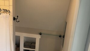A bathroom with a white sink, a towel rack, and a storage cabinet with baskets.