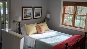 A bedroom with a bed, bedside tables, a window with blinds, and a ceiling light.