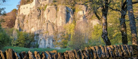 A stone wall in front of a building on a hill.