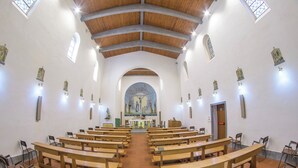 A church interior with wooden pews arranged in rows, a central altar, and a large mural on the back wall. - Pastor Angelicus - Casa per Ferie (Chiusi della Verna)
