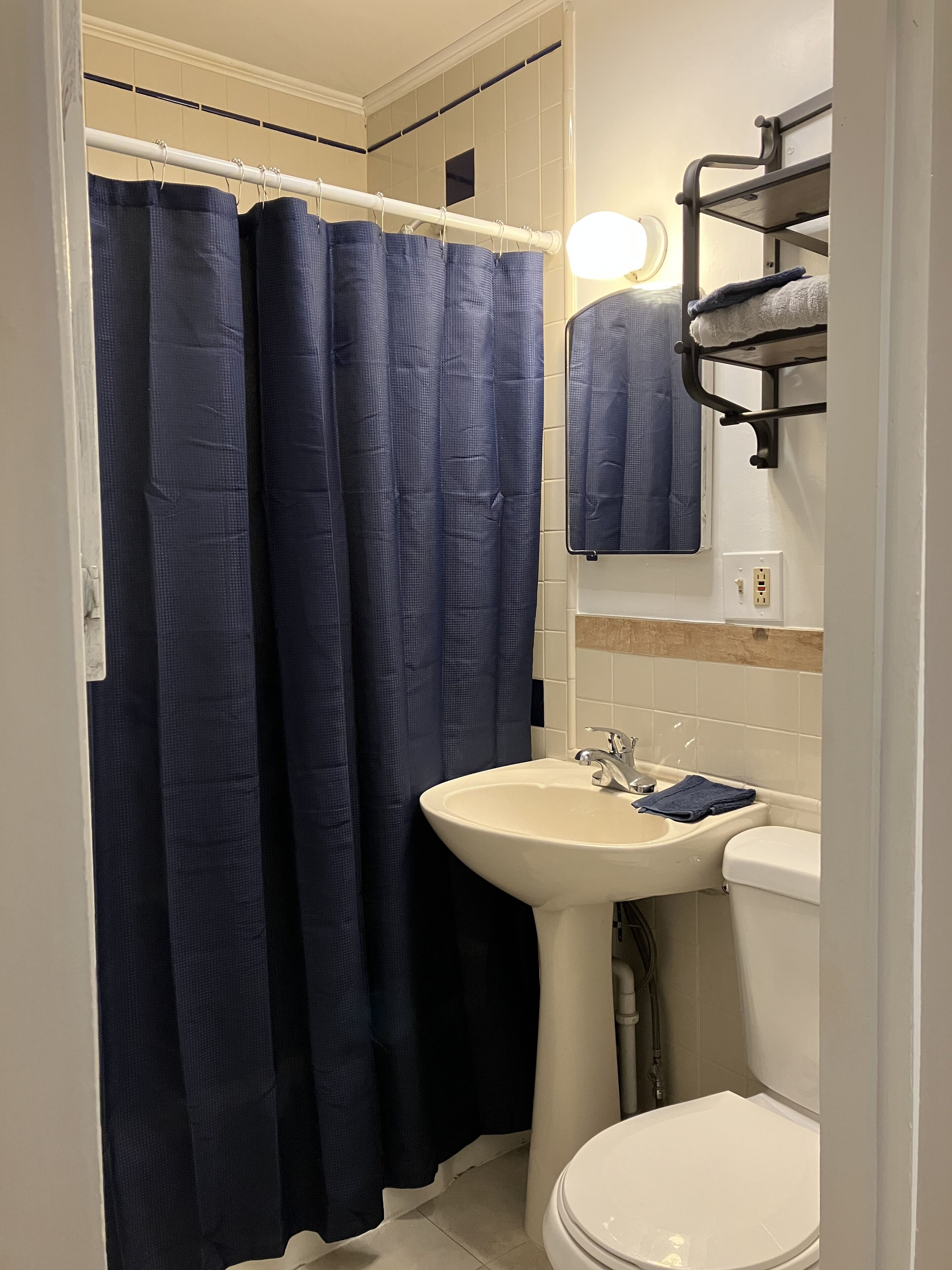 Un baño con lavamanos blanco, inodoro y cortina de ducha.