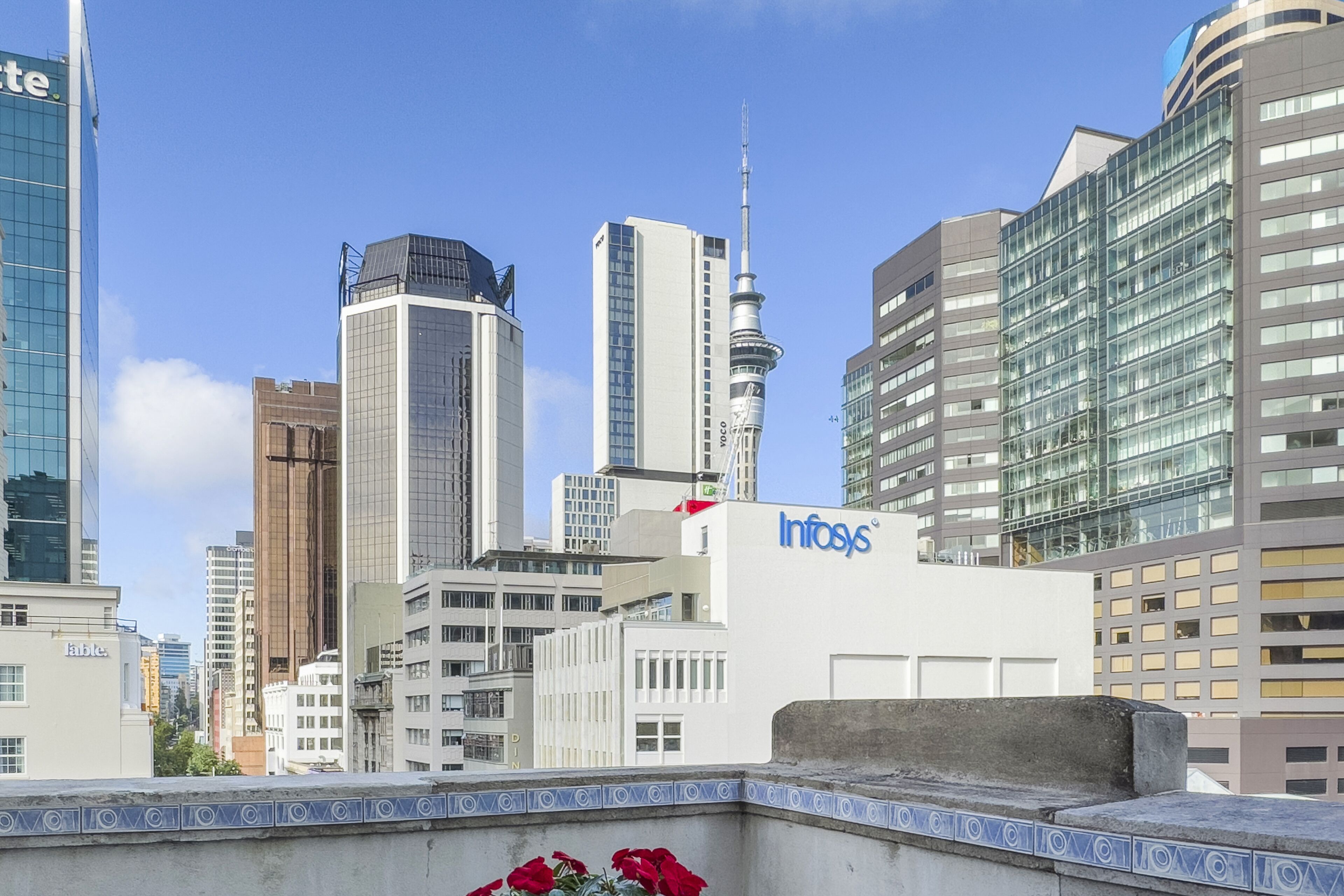 A cityscape with modern buildings, including a prominent tower with a spire.