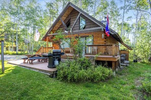En stuga av trä med en veranda, picknickbord och en flagga.