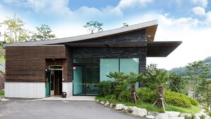 A modern building with a sloped roof, large glass windows, and a stone facade. - Happiness CC Hotel (Naju)
