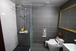 Uma casa de banho moderna com chuveiro, sanita e lavatório.