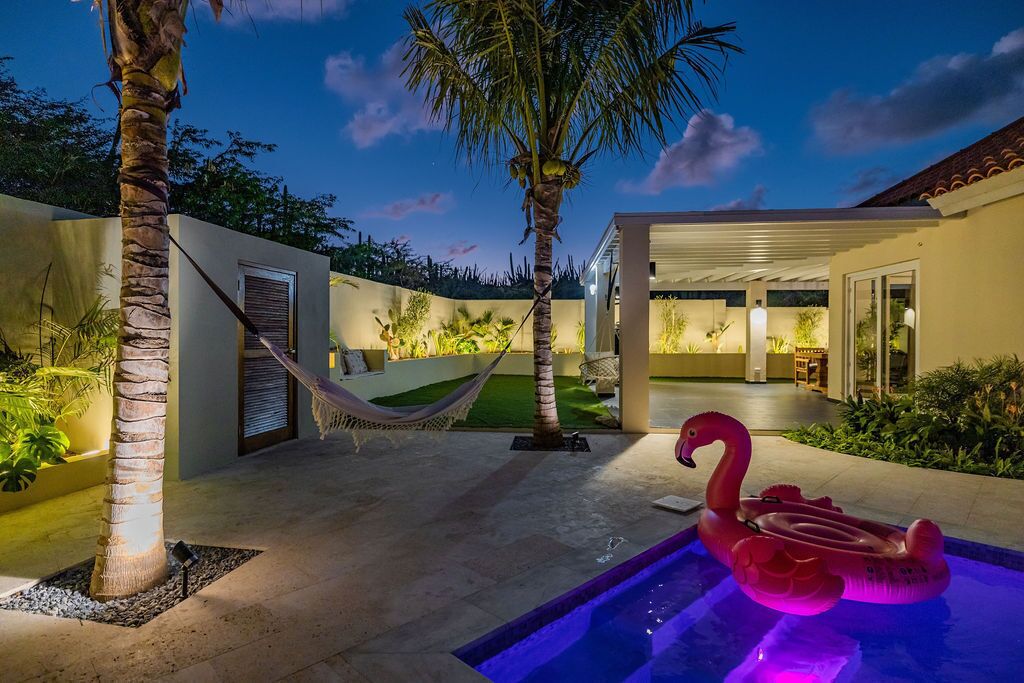 A pool area with a flamingo float, palm trees, and a hammock.