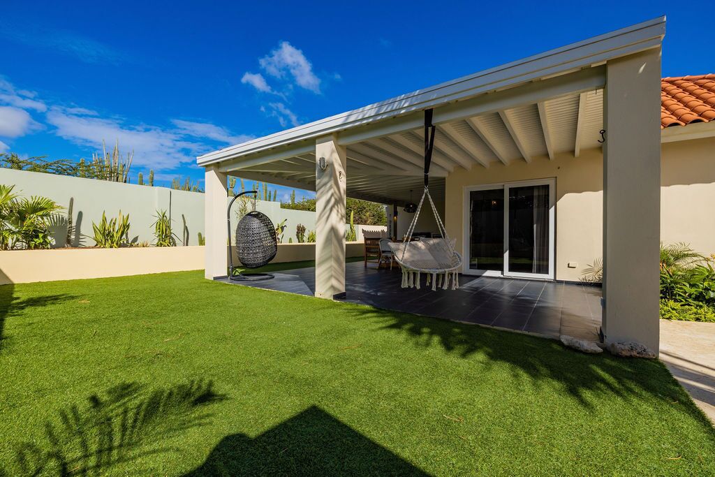 A modern house with a covered patio, a swing chair, and a large decorative ball.