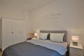 Una camera da letto con un letto, comodini, un armadio e un elemento decorativo a parete.