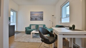 Ein modernes Wohnzimmer mit einem grünen Sofa, einem schwarzen Sessel, einem weißen Couchtisch und einem Bild an der Wand.