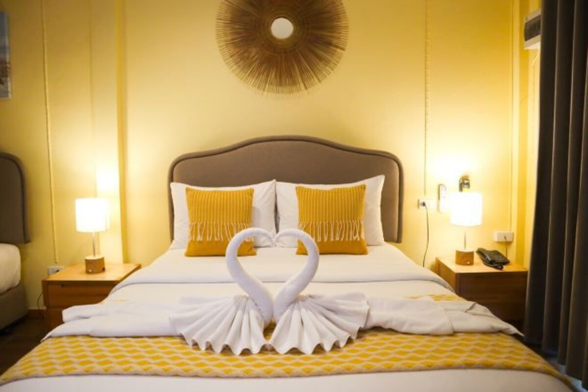 A hotel room with a neatly made bed, two bedside lamps, and a wall-mounted circular light fixture.