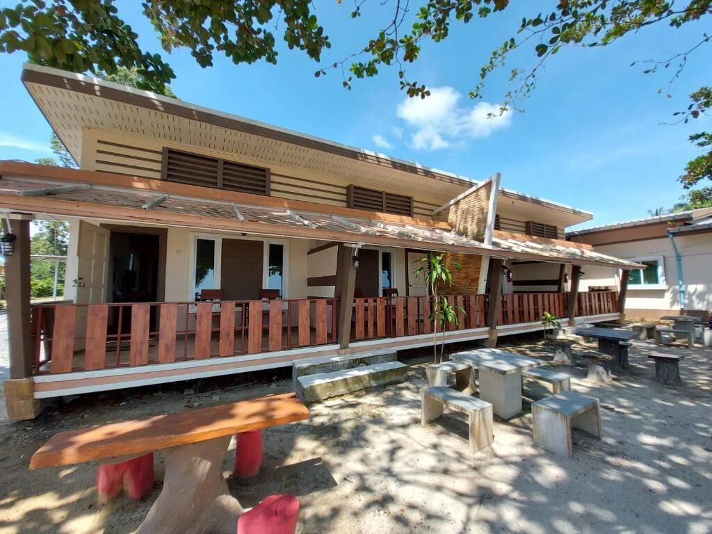A building with a covered outdoor area, benches, and a small garden.