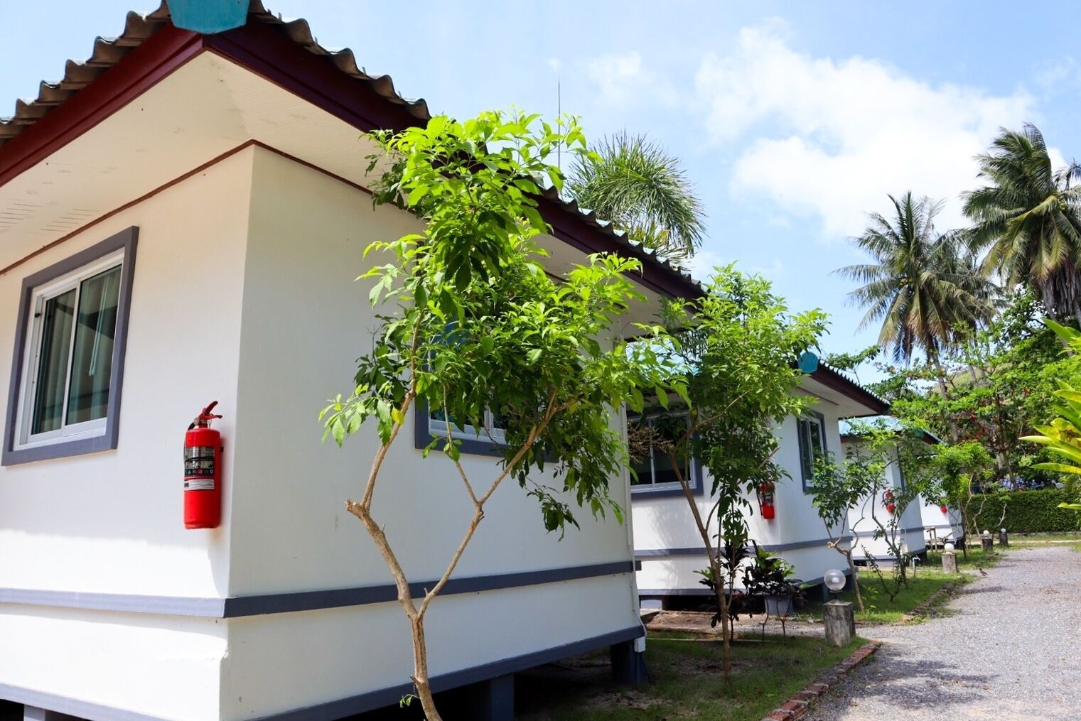 A row of white buildings with blue trim, each with a window and a fire extinguisher mounted on the wall.
