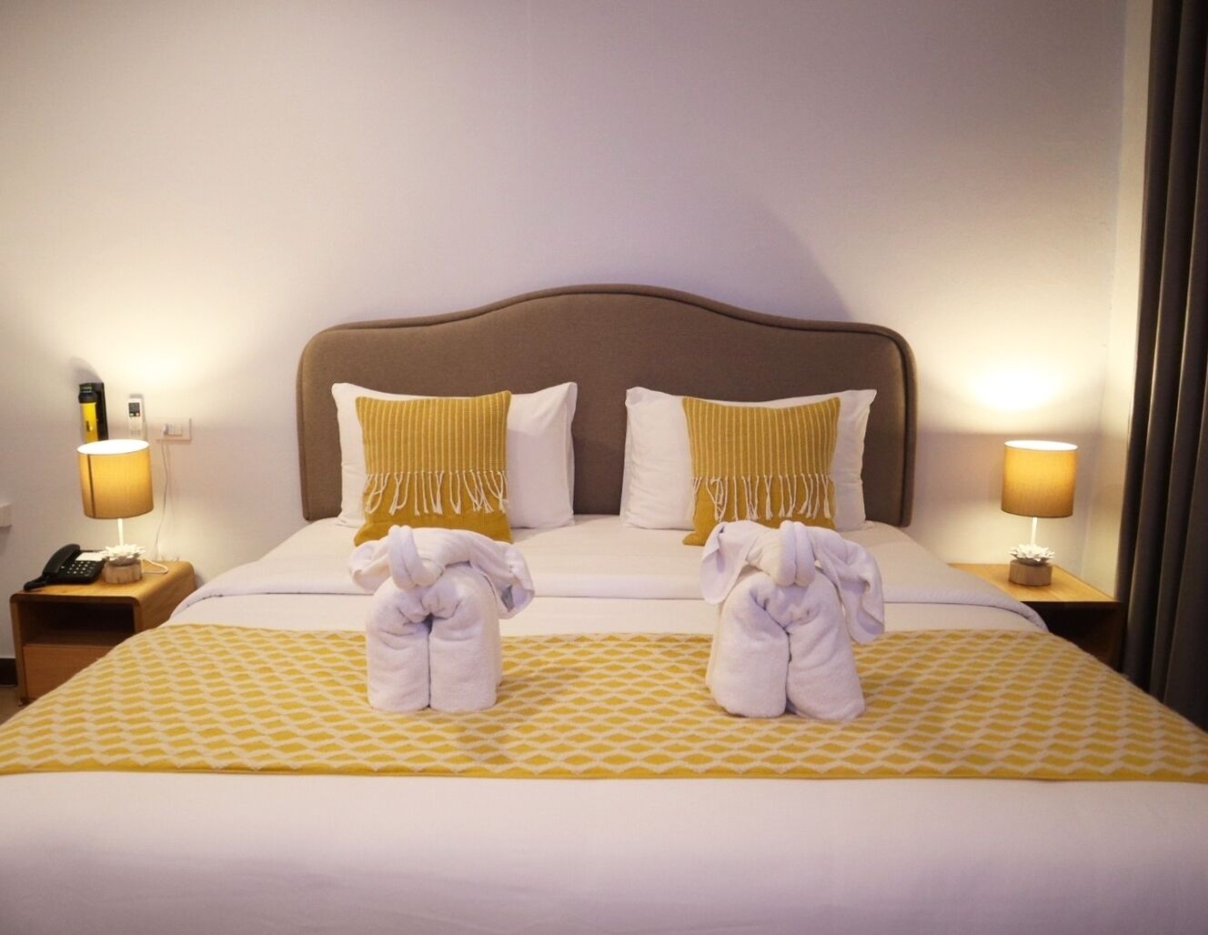 A hotel room with a large bed, two bedside tables, and a nightstand with a lamp.