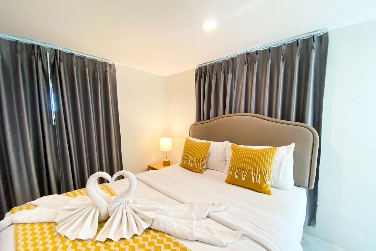 Una habitación de hotel con cama, cortinas, mesita de noche y lámpara.