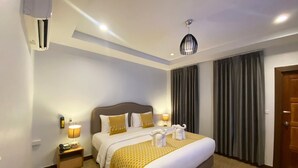 Habitación de hotel con una cama grande, una mesita de noche con lámpara, teléfono y aire acondicionado instalado en la pared.