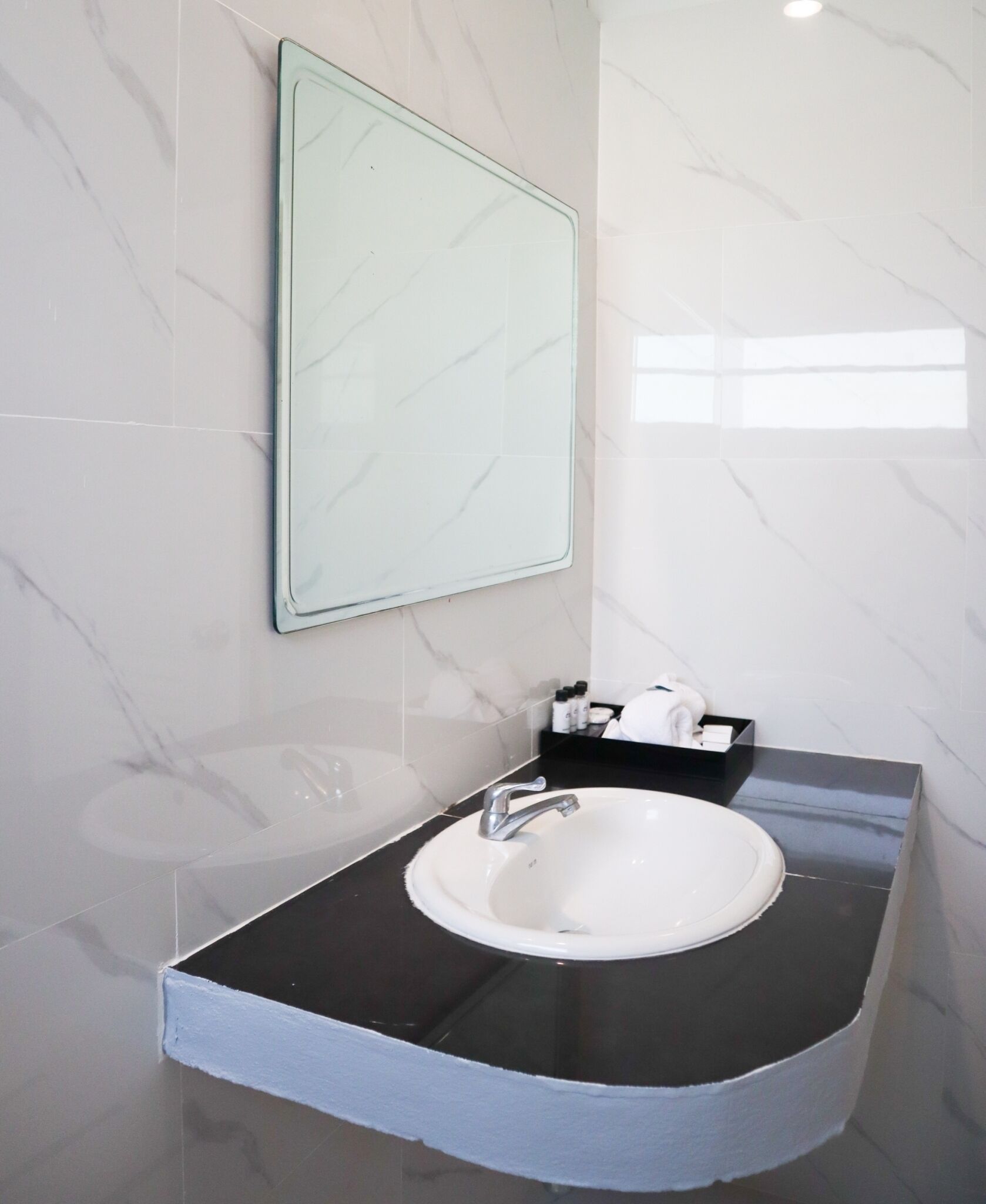 A bathroom with a white sink, black countertop, and a mirror.