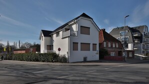 Een woonhuis met twee verdiepingen, een balkon, een garage en een gedeelte van rode baksteen.