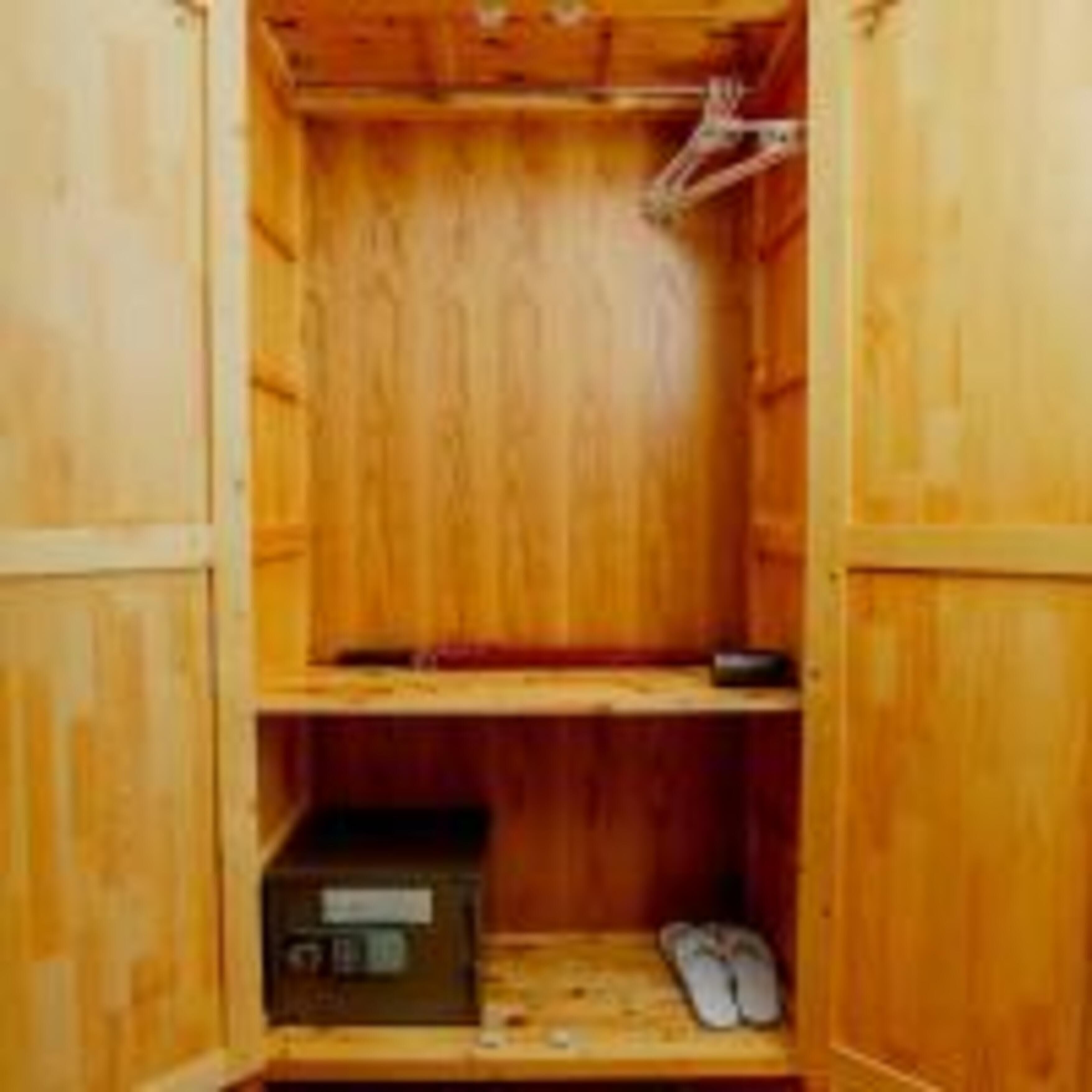 A wooden closet with shelves and a lower compartment containing a box and shoes.