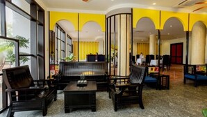 Un hall d’entrée avec un espace salon, de grandes fenêtres et un mur d’accent jaune.