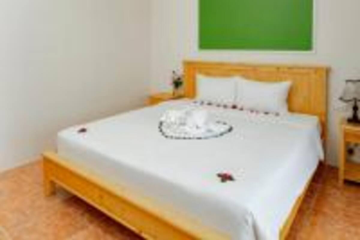 A hotel room with a bed, a green wall, and a wooden headboard.