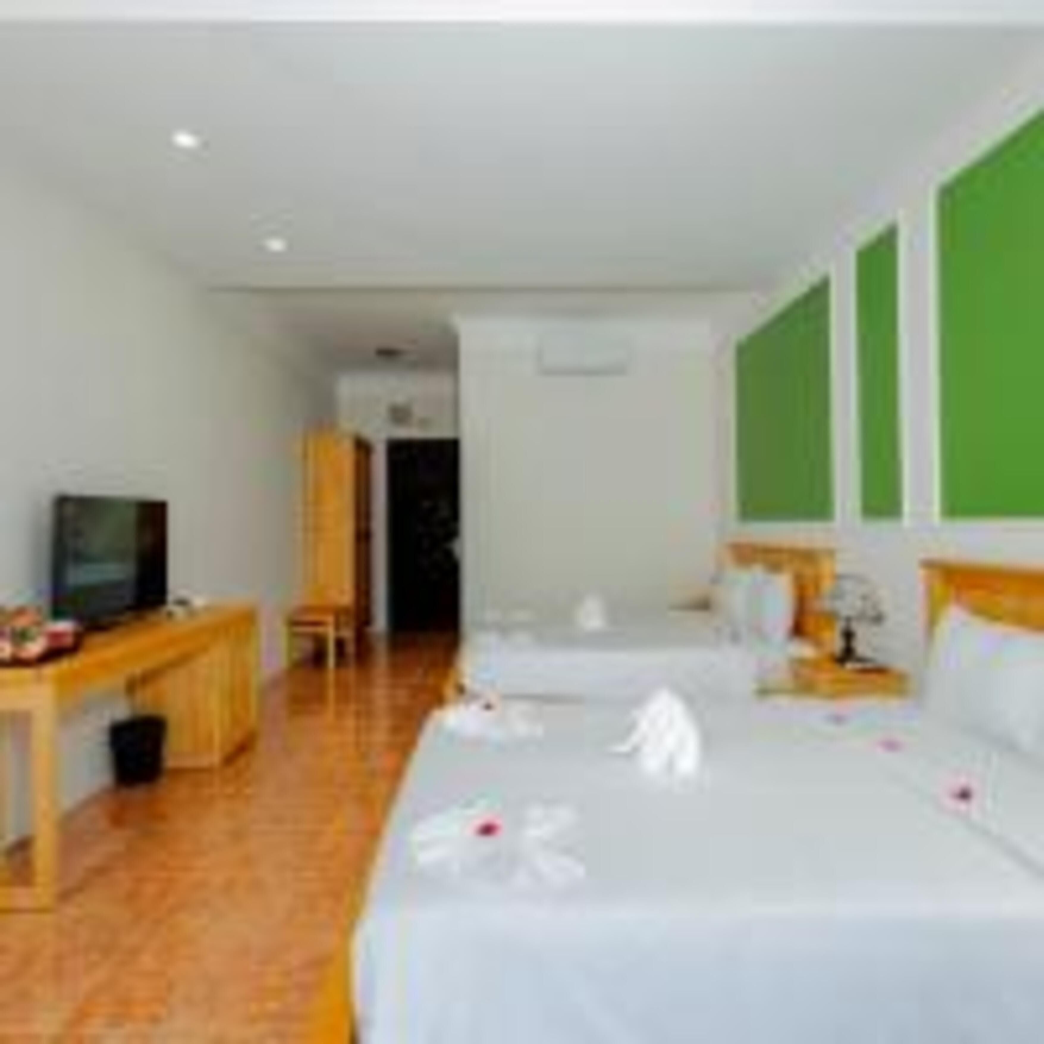 Ein Hotelzimmer mit zwei Betten, einem Schreibtisch mit Fernseher und einer grünen Wand.