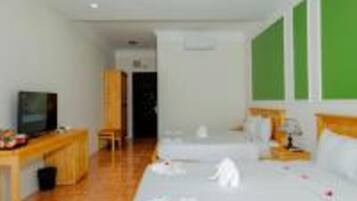 Ein Hotelzimmer mit zwei Betten, einem Schreibtisch mit Fernseher und einer grünen Wand.