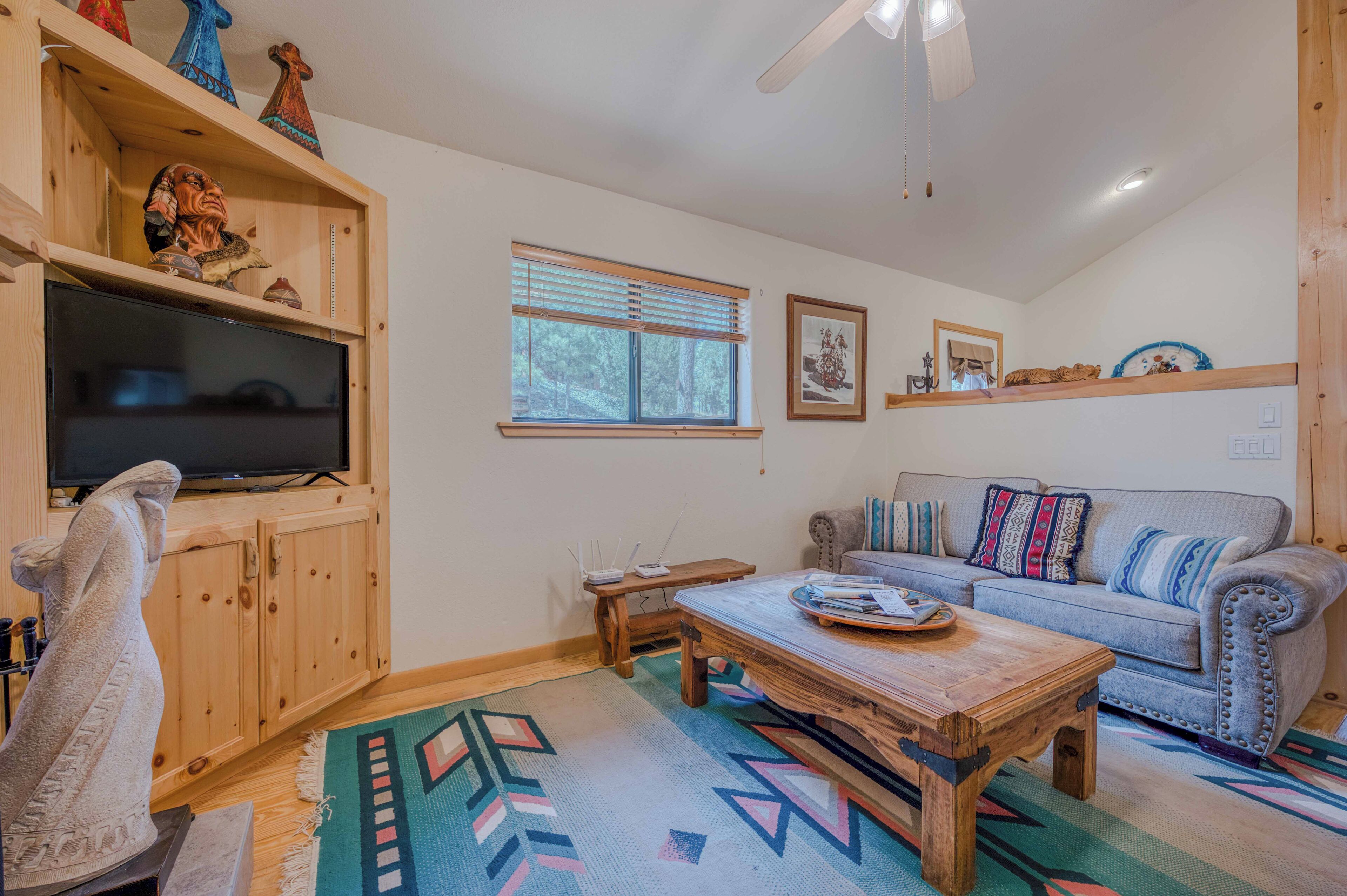 A cozy living room with a wooden cabinet, a television, a sofa, and a coffee table.