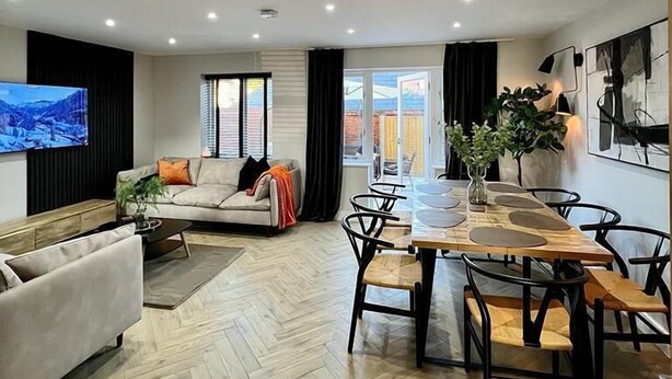 Ein modernes Wohnzimmer mit einer Couch, einem Couchtisch und einem Essbereich mit Stühlen.