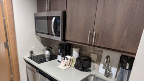 Uma cozinha moderna com eletrodomésticos de aço inoxidável, micro-ondas embutido, torradeira e pia.