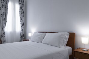 Ein ordentlich bezogenes Bett mit weißen Bettwäsche, einem hölzernen Kopfteil und zwei Nachttischlampen auf einem Holznachttisch.