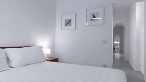 Quarto de hotel moderno com uma cama grande, uma mesa de cabeceira e duas quadros na parede.