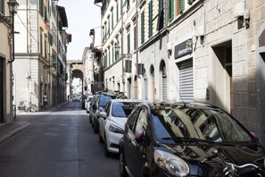 Eine enge Straße mit geparkten Autos und Häusern mit Fensterläden.