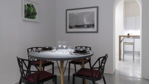 Uma área de refeições com uma mesa redonda, quatro cadeiras e duas obras de arte emolduradas na parede.
