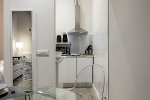Une cuisine moderne avec des armoires blanches, une hotte de cuisinière en acier inoxydable et une machine à café.