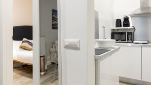 Ett modernt hotellrum med en säng, ett litet pentry och utsikt över stadsbilden.