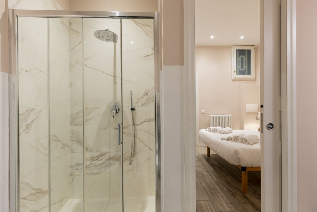 A modern bathroom with a glass-enclosed shower and a wooden floor.
