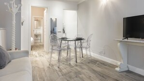 Ett modernt vardagsrum med en matplats, en platt-TV och en soffa i ljusa färger.