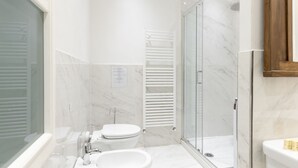 Uma casa de banho moderna com banheira, sanita e chuveiro.