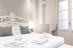 A hotel room with a large bed, white headboard, grey pillows, and neatly folded towels on the bed. - Fiesolana Loft - Florence (Firenze)