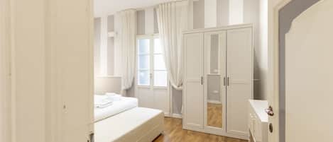 Un dormitorio con cama, armario y ventana con cortinas.