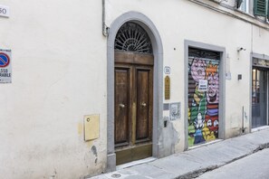 A building with a large wooden door, a metal gate, and a colorful mural on the adjacent wall.