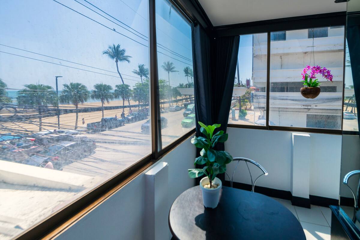 A room with a large window overlooking a street with palm trees and parked cars.