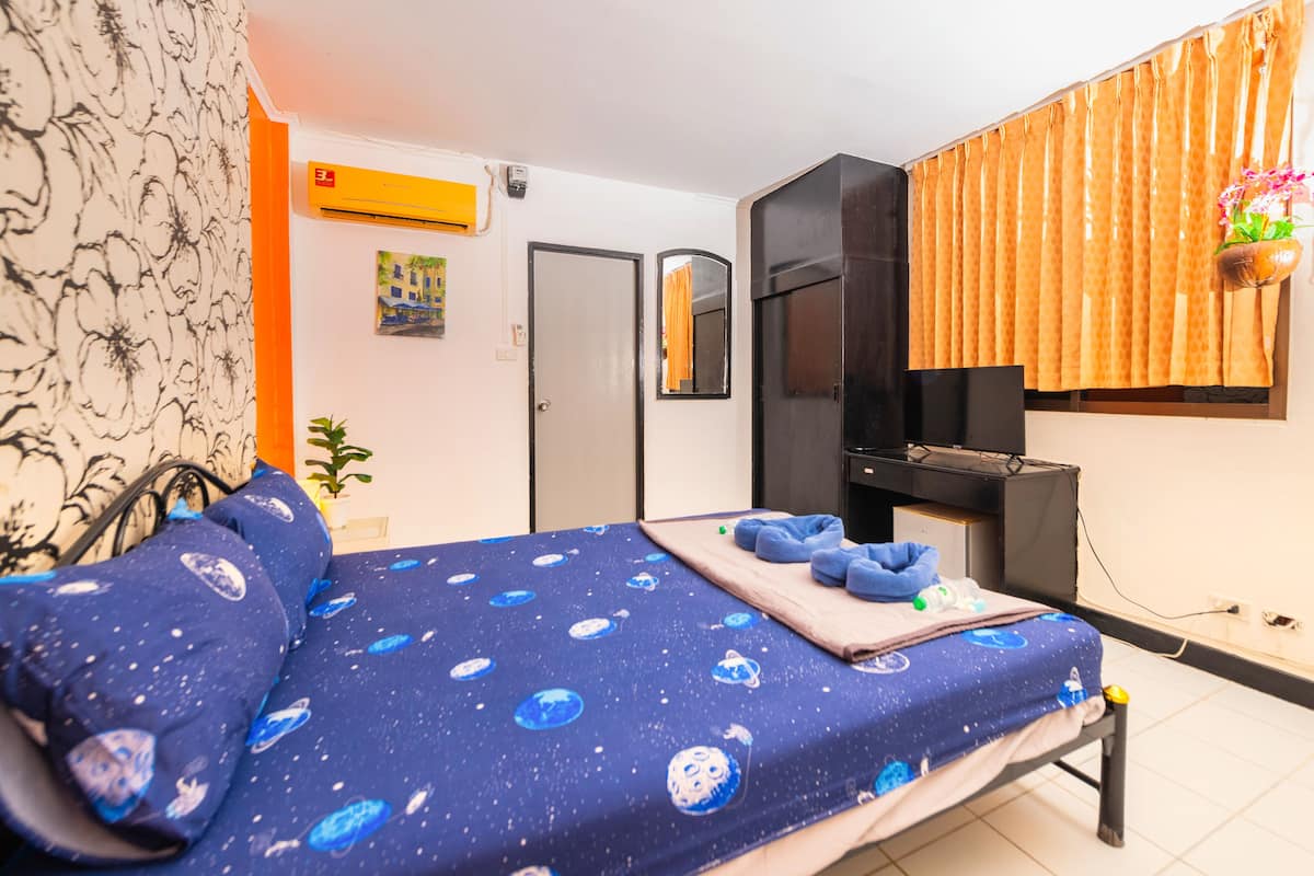 A bedroom with a bed, a wardrobe, a mirror, and a window with curtains.