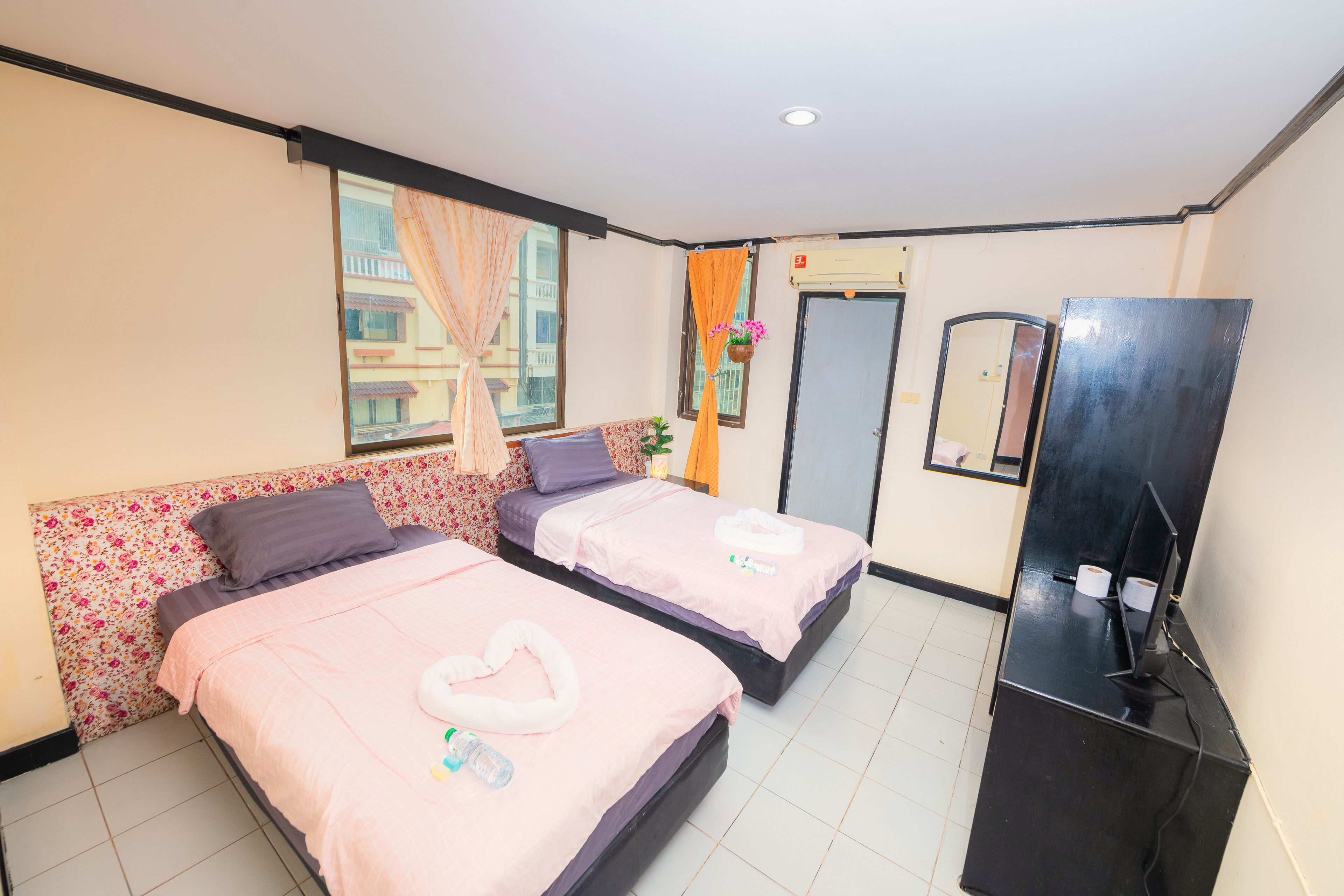 Una camera d'albergo con due letti, una TV a schermo piatto e un minibar.