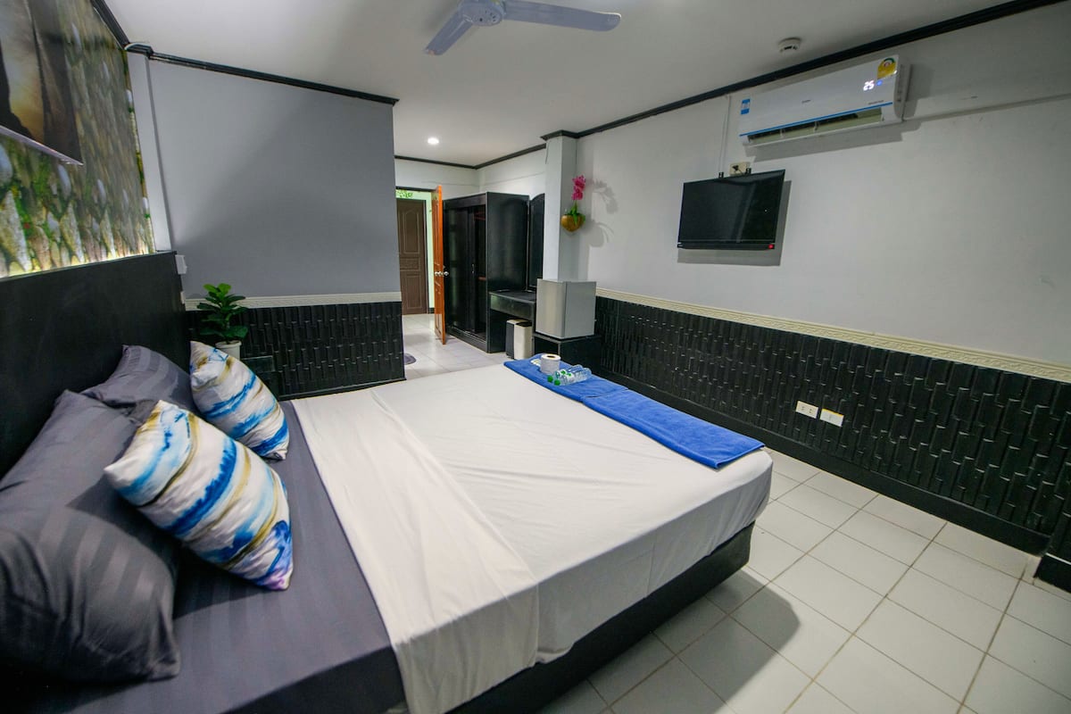 A modern hotel room with a large bed, a flat-screen TV, and an air conditioning unit.