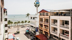 A coastal hotel with multiple floors, balconies, and a view of the sea. - Happy Jomtien - Direct Beach Access, Sea View & Central Location (Pattaya)